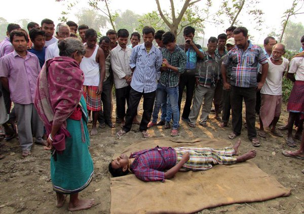In this photograph taken on March 25, 2015, neighbours and family members of deceased farmer Nityagopal Barman (43) stand around his body after he commited suicide at his home in Dhupguri village, in the Jalpaiguri district of West Bengal state. Family members found the body of Barman, who commited suicide, hanging on a tree at his home. Farmers in different parts of Bengal committed suicide after being unable to repay his agricultural loans despite a bumper crop, taking the toll in the state to eight. AFP PHOTO / AFP / STR