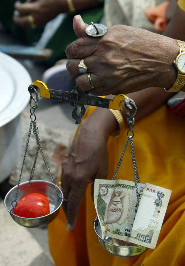 Indian opposition party activist weighs a tomato with a 500 Indian Rupee note during a demonstration outside government offices in Hyderabad on October 25, 2008. The demonstration was held in protest at rising prices of essential commodities. AFP PHOTO/Noah SEELAM / AFP / NOAH SEELAM