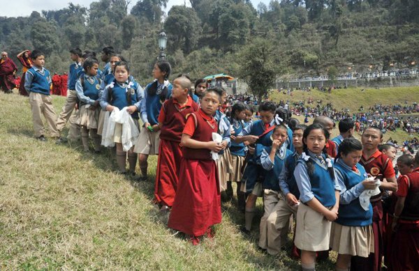 Young school-children wait for a glimpse of the Dalai Lama as Buddhist monks and devotees gather for the inauguration of the 130 foot Lord Buddha statue by Tibetan spiritual leader, the Dalai Lama at Buddha Park in Rabong in South Sikkim on March 25, 2013. The Buddha park named 'Tathagatatsal' covers an area of 23 acres and was formally inaugurated by Tibetan spiritual leader Dalai Lama. AFP PHOTO/Diptendu DUTTA / AFP / DIPTENDU DUTTA