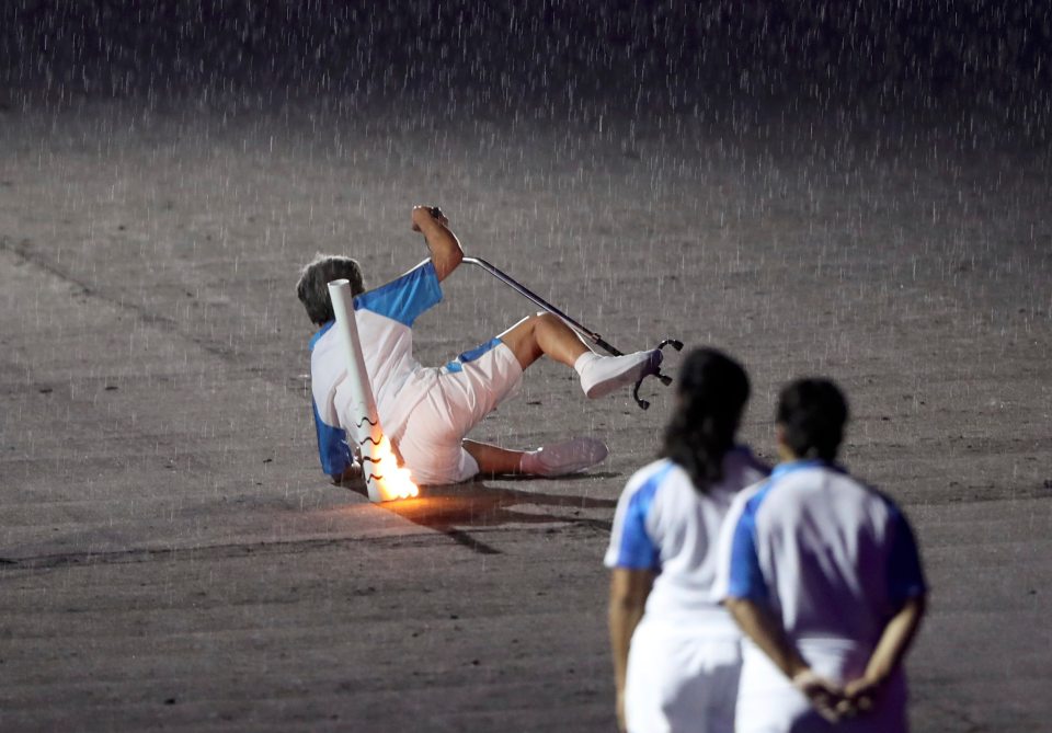 2016 Rio Paralympics - Opening ceremony - Maracana - Rio de Janeiro, Brazil - 07/09/2016. Brazilian Paralympic runner Marcia Malsar falls while carrying the torch as rain falls during the opening ceremony. REUTERS/Ueslei Marcelino FOR EDITORIAL USE ONLY. NOT FOR SALE FOR MARKETING OR ADVERTISING CAMPAIGNS.
